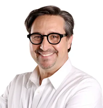 Portrait of Emmanuel Pacheco smiling, wearing glasses and a white shirt